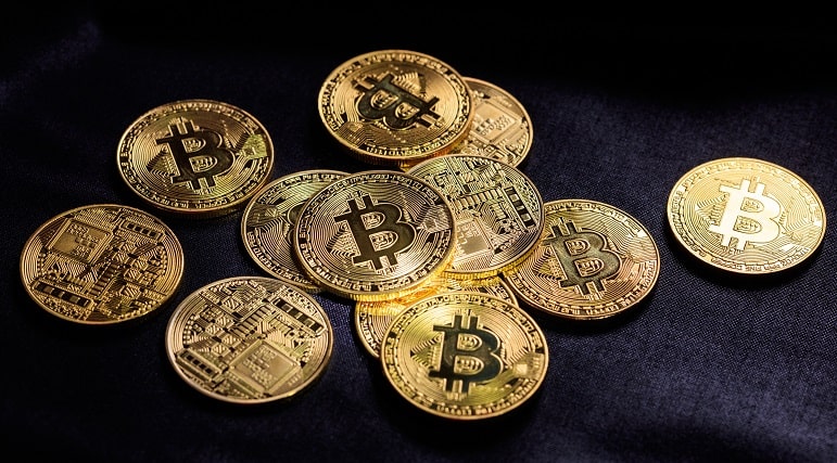 Varios bitcoins sobre un fondo de tela negro.